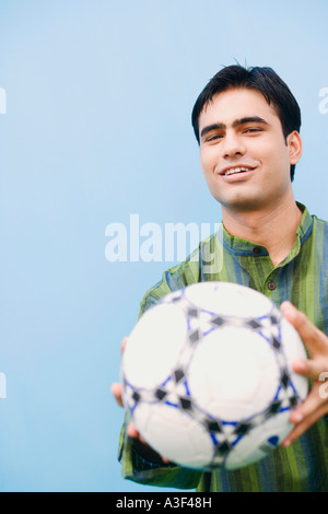 Porträt eines jungen Mannes hält einen Fußball und lächelnd Stockfoto