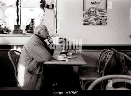 Mann mit Kaffee und rauchte eine Zigarette bei Tesco Café Restaurant London, England, Großbritannien, UK. Stockfoto