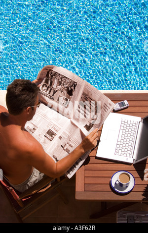 über Aufnahme von Mann mit Laptop lesen Zeitung und Handy-Pool Pause eine von Büro in Kontakt bleiben Stockfoto