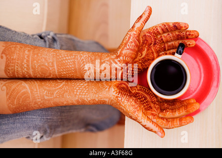 Nahaufnahme einer Frau Henna tätowiert Händen mit einer Tasse Tee Stockfoto