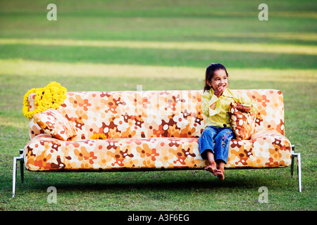 Mädchen sitzen auf einer Couch auf dem Rasen und lächelnd Stockfoto