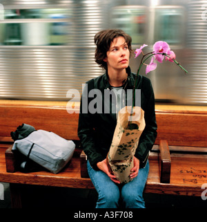 Mädchen 30 sitzen in New York U-Bahn halten Orchidee Hintergrund unscharf Stockfoto