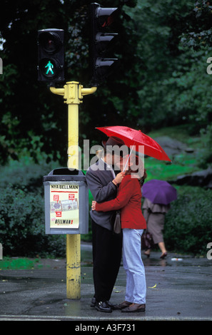 Paar küssen unter roten Regenschirm an regnerischen Tag in Stockholm Schweden Stockfoto