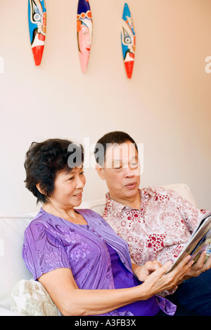 Nahaufnahme eines älteren Mannes und eine reife Frau, die eine Zeitschrift liest Stockfoto