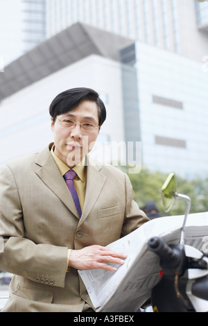 Porträt eines Geschäftsmannes hält eine Zeitung Stockfoto