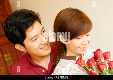 Nahaufnahme einer jungen Frau mit Blumen mit einem jungen Mann Stockfoto