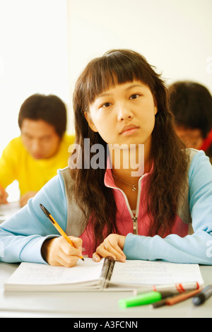 Porträt einer jungen Frau sitzt an einem Schreibtisch im Klassenzimmer Stockfoto
