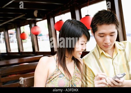 Nahaufnahme eines jungen Mannes mit einem Mobiltelefon neben einer jungen Frau Stockfoto