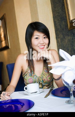 Porträt einer jungen Frau in einem Restaurant mit der Hand am Kinn sitzen Stockfoto