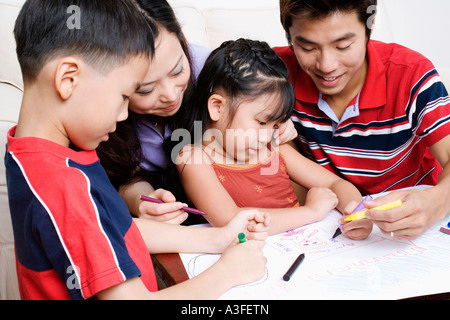 Nahaufnahme von zwei Kindern, die Zeichnung auf Papier mit ihren Eltern Stockfoto