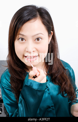 Porträt einer jungen Frau Auftragen von Lippenstift Stockfoto