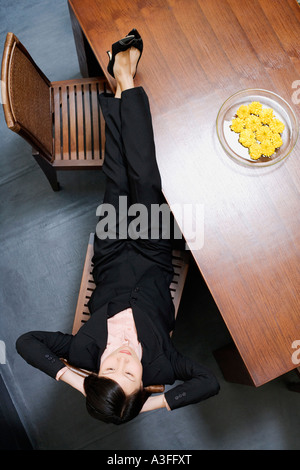 Vogelperspektive Blick auf eine Geschäftsfrau liegen und ruhen ihre Füße auf den Tisch Stockfoto