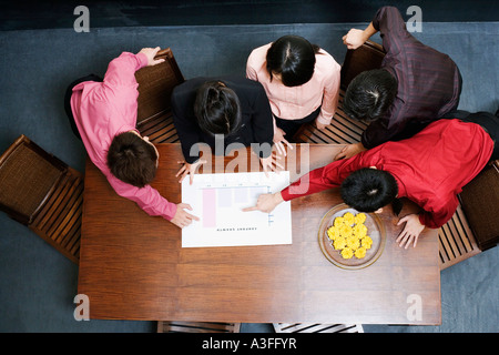 Vogelperspektive Blick auf zwei Geschäftsfrauen und drei Geschäftsleute diskutieren ein Balkendiagramm Stockfoto