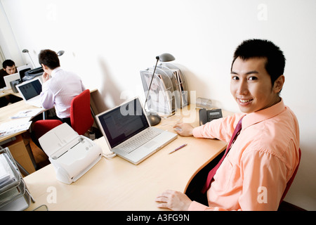Porträt eines Geschäftsmannes lächelnd mit einem anderen Unternehmer im Hintergrund arbeiten Stockfoto