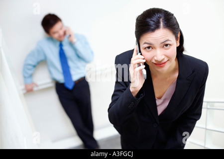 Porträt einer Geschäftsfrau Gespräch auf ein Mobiltelefon mit einem Geschäftsmann, der hinter ihr stehenden Stockfoto
