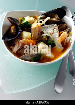 Eine Glasschüssel der französischen Bouillabaisse auf einem blauem Glas Hintergrund redaktionelle Essen Stockfoto