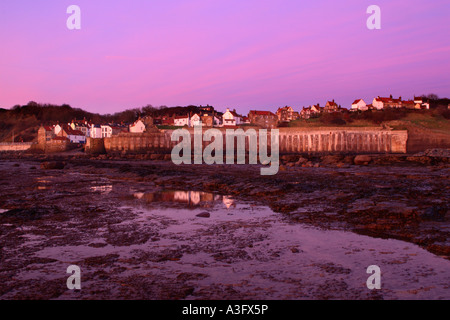 Dorf von Robin Hoods Bay in North Yorkshire zeigt Deich bei Ebbe mit Fels-Pools im Vordergrund in der Morgendämmerung ist Angeln Stockfoto