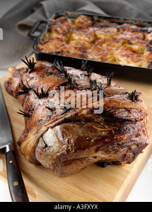 Gebratene Lammkeule auf ein Schneidebrett mit Dauphinoise Kartoffeln redaktionelle Essen Stockfoto