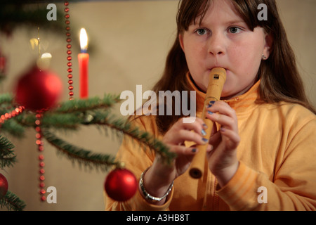 junge Mädchen spielt des Recorders vor einem Weihnachtsbaum Stockfoto