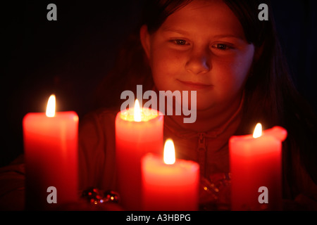 junges Mädchen mit Blick auf die Kerzen einen Adventskranz andächtig Stockfoto