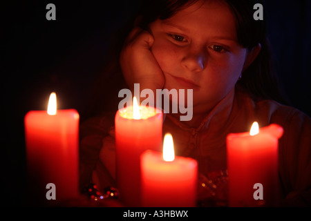 junges Mädchen mit Blick auf die Kerzen einen Adventskranz andächtig Stockfoto