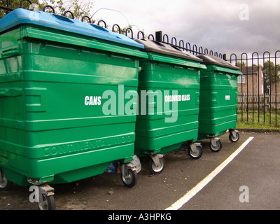 Drei grüne Recyclingbehälter in Industriegröße auf einem Parkplatz, einer für Dosen, einer für farbiges Glas und einer für Papier. Stockfoto