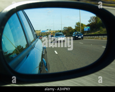 Nahaufnahme des Außenspiegels an einem Auto, das den Verkehr hinter einer Autobahn zeigt. Stockfoto