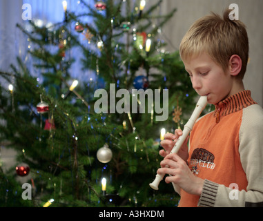 kleiner Junge spielt des Recorders vor einem Weihnachtsbaum Stockfoto