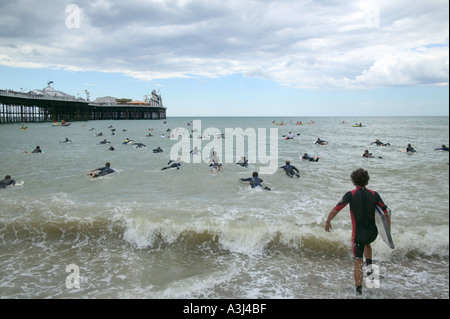 Surfer, die Schwimmen im Meer neben der Palace Pier Brighton an der Surfers gegen Abwasser SAS-protest Stockfoto