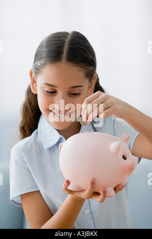 Speichern eine Münze in Sparschwein Mädchen Stockfoto