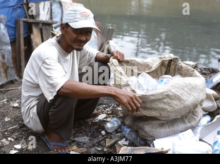 Lächelnd Mann sammeln leere Plastikflaschen am Fluss in einem Slumviertel von Surabaya Ost Java Stockfoto