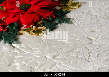 Spitze der dekorierte Geeiste Frucht Weihnachtskuchen mit geprägtem Holly Blättern und roten Weihnachtsstern-Blüten aus Zuckerguss gemacht Stockfoto