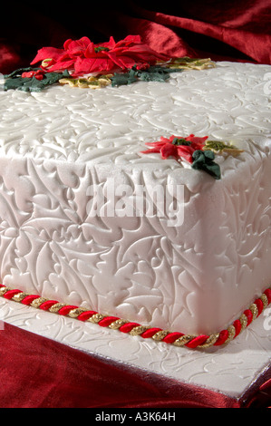 Wunderschön dekoriert Geeiste Frucht Weihnachtskuchen mit geprägtem Holly Blättern und roten Weihnachtsstern-Blüten aus Zuckerguss gemacht Stockfoto