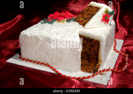 Wunderschön dekoriert Geeiste Frucht Weihnachtskuchen mit geprägtem Holly Blättern und roten Weihnachtsstern-Blüten aus Zuckerguss gemacht Stockfoto
