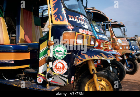 Bunte Tuk-Tuks für den Dienst in der laotischen Stadt Paxxe (Pakse) aufgereiht. Stockfoto