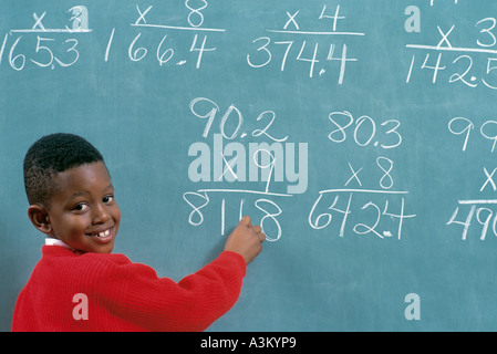 Afrikanische amerikanische männliche Schüler lösen von mathematischen Problemen an Tafel in der Grundschule Klasse Stockfoto