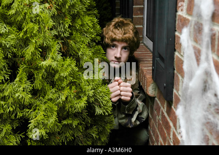 Teenager in den Büschen verstecken kommen, um die Tür für Trick oder Leckereien zu Halloween Kinder erschrecken Stockfoto