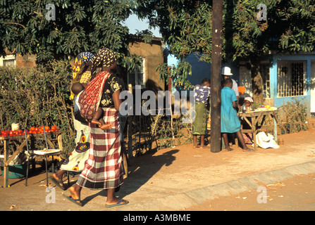 Eine Nachbarschaft in Maputo-Mosambik mit Frauen zu Fuß und tragen Babys auf dem Rücken in Tücher gewickelt Stockfoto