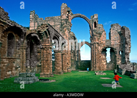 Kinder spielen im Priorat Ruinen Lindisfarne Island, Großbritannien Stockfoto