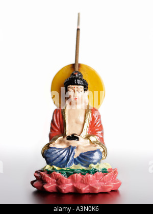 Buddha-Figur mit brennenden Räucherstäbchen auf weißem Hintergrund, Fokus auf Gesicht Stockfoto