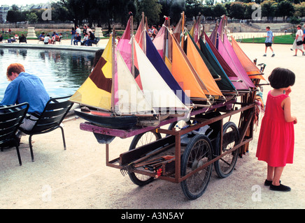 Jardin du Luxembourg, Paris, Jardin du Luxembourg. Mädchen in rotem Kleid farbenfrohe Spielzeug-Segelboote zum Mieten. Großer Bassin. Ile-de-France. Stockfoto