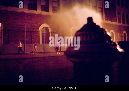 Passanten genießen Sie das Spray von einer offenen Hydranten in einer Straße in Brooklyn New York City USA auf eine heiße Sommernacht Juli 2005 Stockfoto