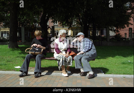 Eine junge Frau und zwei ältere Menschen sitzen auf einer Bank, Polen Stockfoto