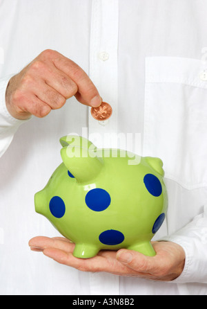 Mann mit weißem Hemd einfügen Münze in piggy Bank Stockfoto