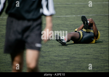 schwarzen verletzten Fußballspieler Rollen auf dem Boden hält sein Bein Stockfoto