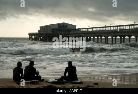 Surfer sitzen am Strand vor Boscombe Pier, Bournemouth, Dorset, England, UK genommen Jan 2007 Stockfoto