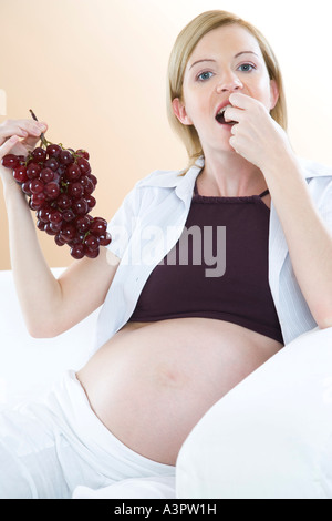 Schwangere Frau essen Trauben Stockfoto