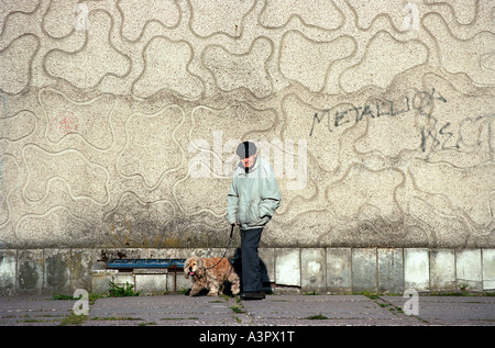 Alter Mann mit Hund zu Fuß entlang einer Betonwand, Kaliningrad, Russland Stockfoto