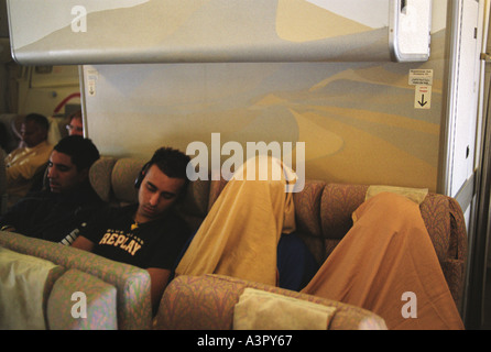 Langstreckenflugzeugflug zwei schlafende Menschen mit Flugdecken über den Kopf gezogen. Alle Sitze sind überfüllt und haben den Flug genommen. 2000er Jahre Stockfoto