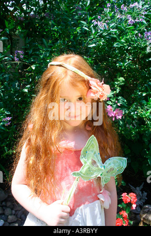 rote lange Haare unter der Leitung Mädchen halten Karnevalsmaske Stockfoto